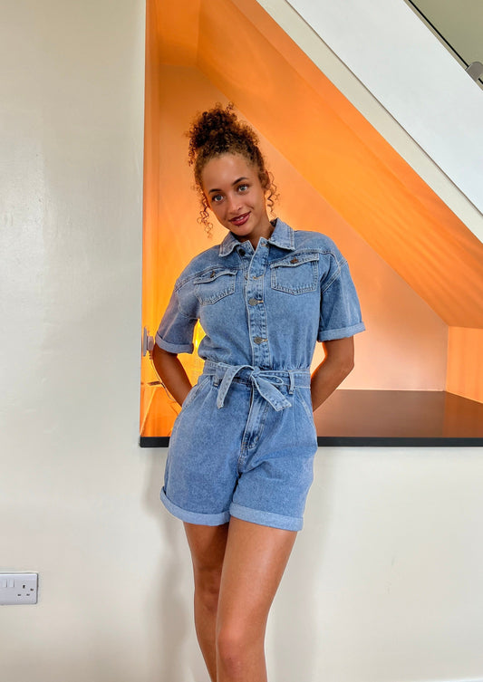 Introducing our sustainably made premium denim playsuit. This versatile garment features a button front and a tie belt, perfect for any occasion.